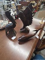 Front view of three wooden figurines (whale, sailfish, pelican) on table
