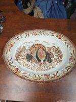 Front view of oval porcelain platter with turkey scene and harvest border