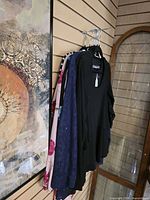 Side view of six garments on hangers showing colours and fabrics