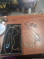 All six necklaces laid out on table and tray