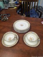 Overview of all pieces: two teacup and saucer sets with stack of six plates