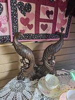 pair of bronze-tone resin peacock bookends on lace tablecloth