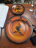 Front view of both painted wooden plates showing designs and colours