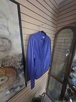 Front view of purple leather jacket hanging on slat wall