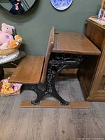 Side view showing cast iron frame, wood seat, and lift-up desktop