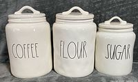 front view of three labeled canisters with lids on