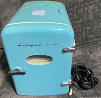 Front view of aqua Frigidaire mini fridge with latch and window, AC power cord shown