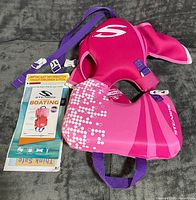 Front view of pink/purple Stearns infant life jacket with pamphlet