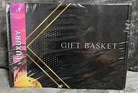 Shrink-wrapped black gift box front with diagonal gold stripe and ‘Gift Basket Luxury Gift Set’ text