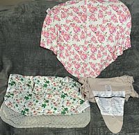 Three items laid out: pink floral cover, green floral blanket with grey minky side, beige Moby wrap