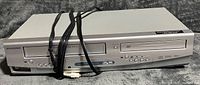 Front view of silver Sylvania DVD/VCR combo with controls and display