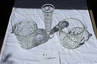 Group shot of three clear crystal/pressed glass pieces: bud vase and two ice buckets