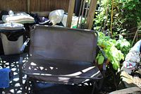 Front view of brown metal outdoor glider bench showing seat, backrest and armrests