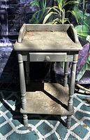Full view of gray distressed wood side table showing drawer, gallery sides and lower shelf
