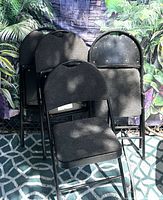 Four stacked padded folding chairs showing front upholstery and metal frames