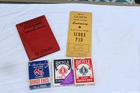 All five items laid out on white cloth: Culbertson book, Goren score pad, three decks of playing cards