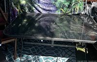 full view of glass-top patio table showing frame and umbrella hole