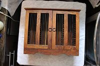 Front view of closed cabinet showing doors with metal slats and ring pulls