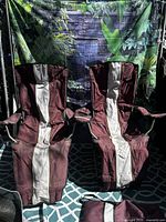 Front view of both burgundy camping chairs showing fabric, frames, footrests and cup holders