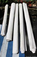 Five rolled white blinds laid out on ground