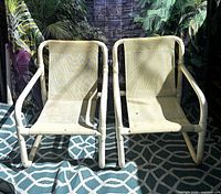 Two of the four off-white PVC sling patio chairs