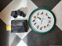 Front view of lot: Audubon clock, Bushnell binoculars with case and cloth