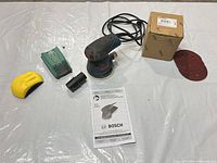 Entire lot laid out: sander, pads, adapter, discs, manual