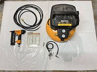Top view of entire lot showing compressor, hose, nailer, fasteners, inflator and adapter