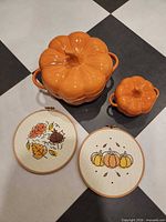 Full lot showing both ceramic pumpkin bowls and two cross-stitch hoop arts
