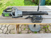 Leaf blower with battery attached and charger on table