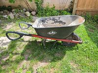 Side view of Garant wheelbarrow showing black tub, red frame, loop handles, flat pneumatic tire