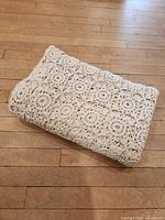 Folded crocheted ivory blanket showing texture and thickness