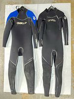 Front view of both O'Neill wetsuits hanging side-by-side