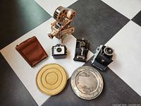 Group shot of all cameras, film cans, reel and wood projector model