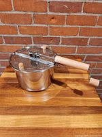 Side view of stainless steel Whirley Pop popper with wooden handle and crank.