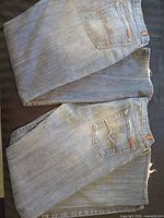Two folded pairs of blue denim jeans showing back pockets and labels