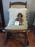 Front view of rocking chair with pillow and doll placed on seat