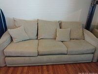 Full view of tan sofa showing cushions and pillows