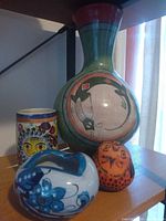 All four folk art pieces displayed together on shelf