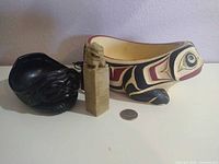 All three items with coin for scale: painted frog bowl, black frog bowl, soapstone seal