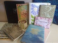 Group of journals, prayer cards, binder clips box, and additional notebooks