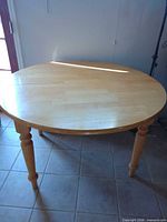 Full view of round light wood table on tiled floor