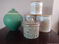 Group view of green lidded pot, speckled jar and two floral canisters