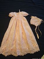 Lace baby gown and matching bonnet displayed flat