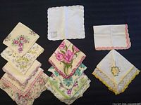 Group shot of all thirteen hankies folded and laid out showing variety of prints and crochet edges