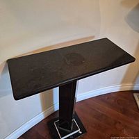 Full view of black granite pedestal table showing top, column, and base