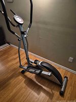 Side view of full elliptical trainer showing frame, pedals and flywheel