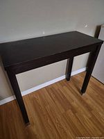 Full view of dark brown console table against wall