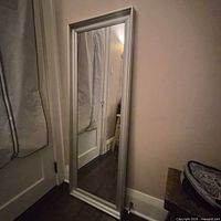 Front view of silver metal full-length mirror leaning against wall