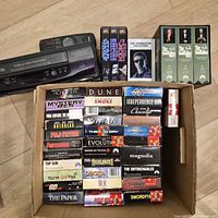 Samsung VCR with remote on top and selection of VHS tapes including Star Wars set and boxed Terminator title